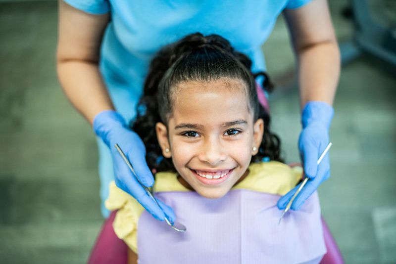 A little girl is smiling while sitting in a dental chair.