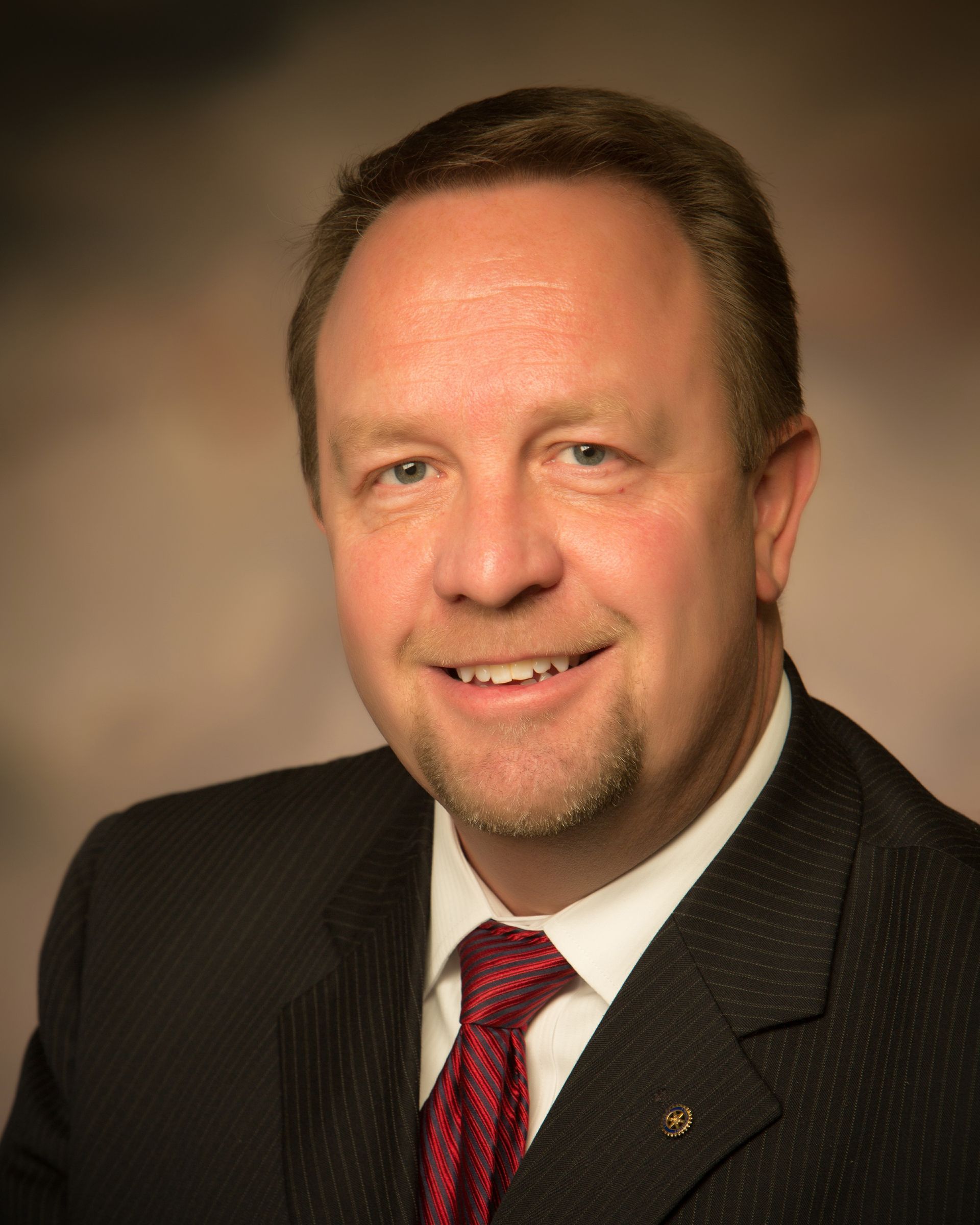 Un hombre con traje y corbata sonríe para la cámara.