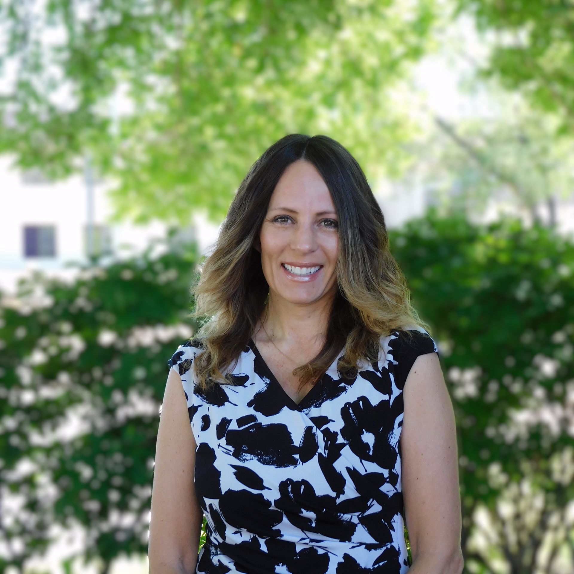 Una mujer con un vestido blanco y negro sonríe para la cámara.