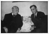 A black and white photo of two men and a baby.