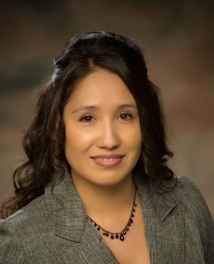 Una mujer con traje y collar sonríe para la cámara.