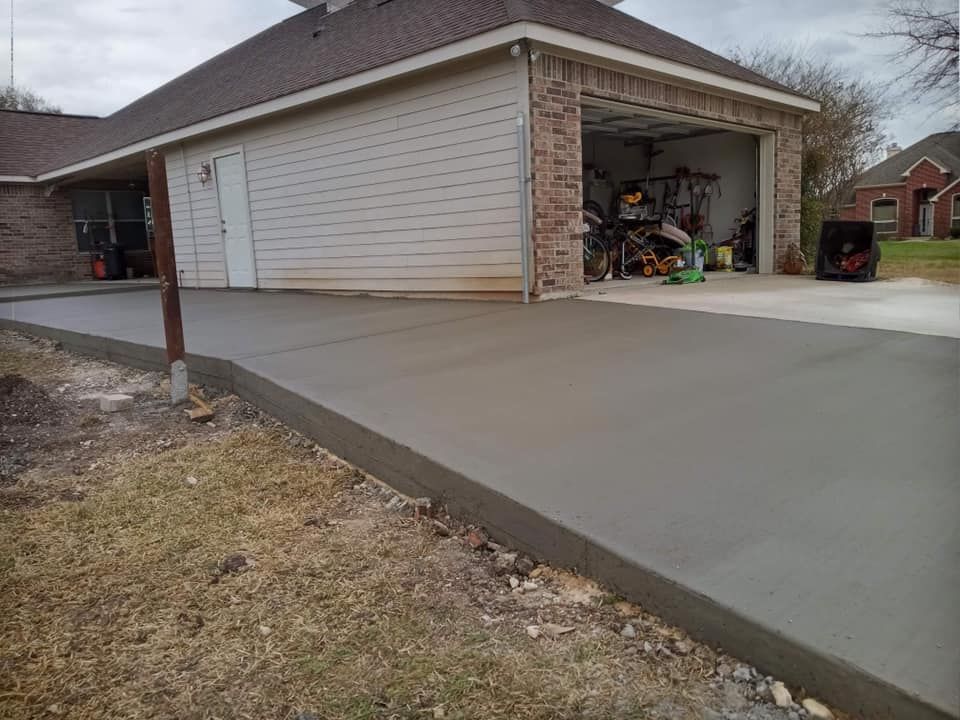 New concrete driveway leading to a garage; low angle, overcast day.