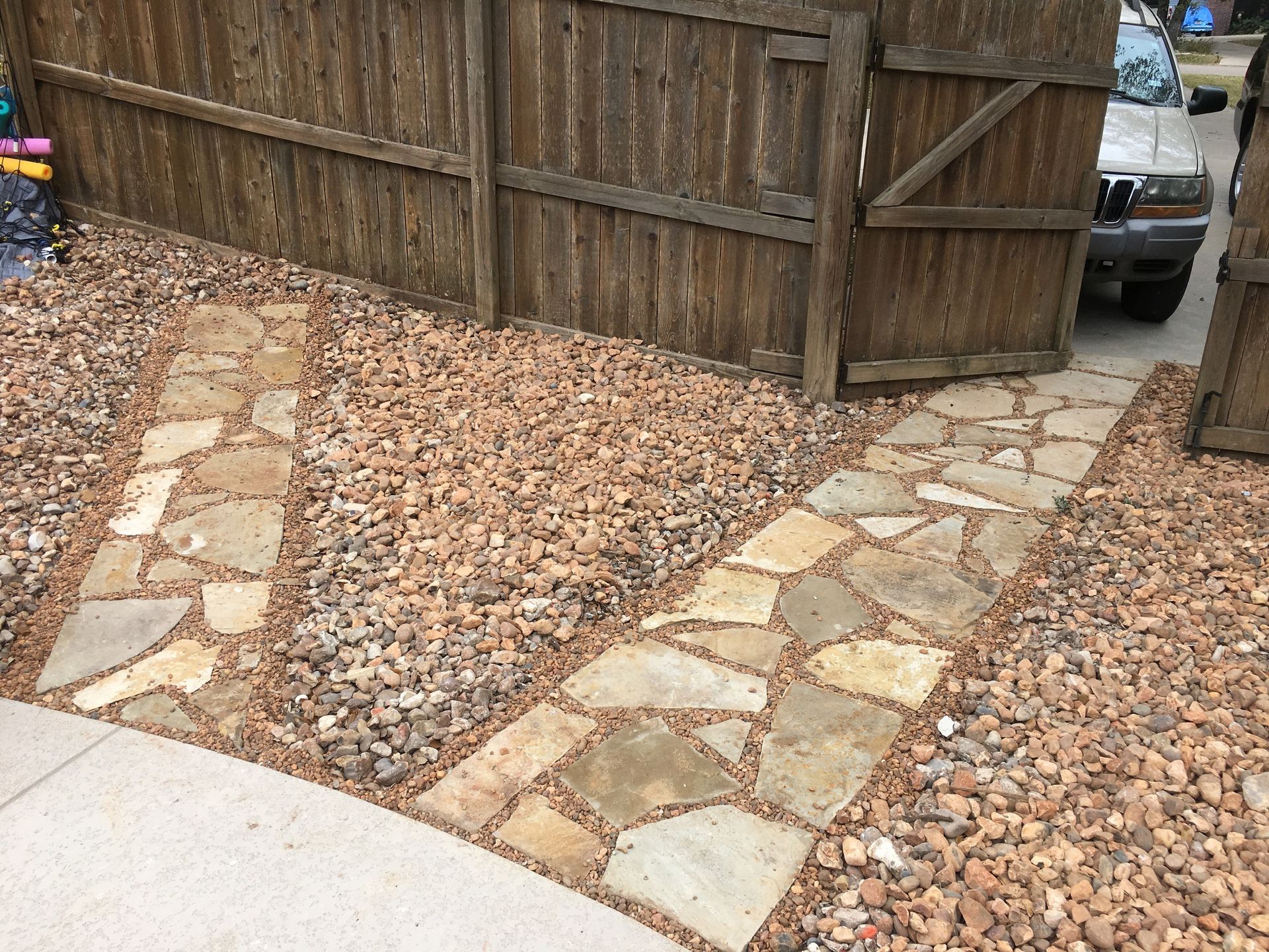 Stone pathways through gravel lead to a wooden gate.