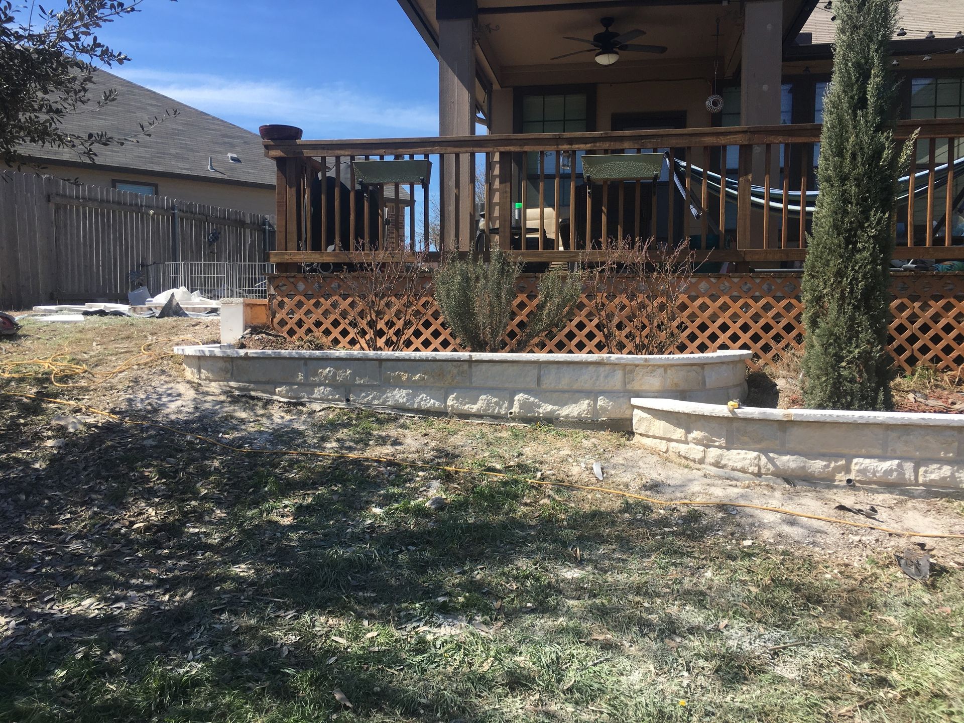 Backyard with a raised deck, retaining wall, and landscaping.