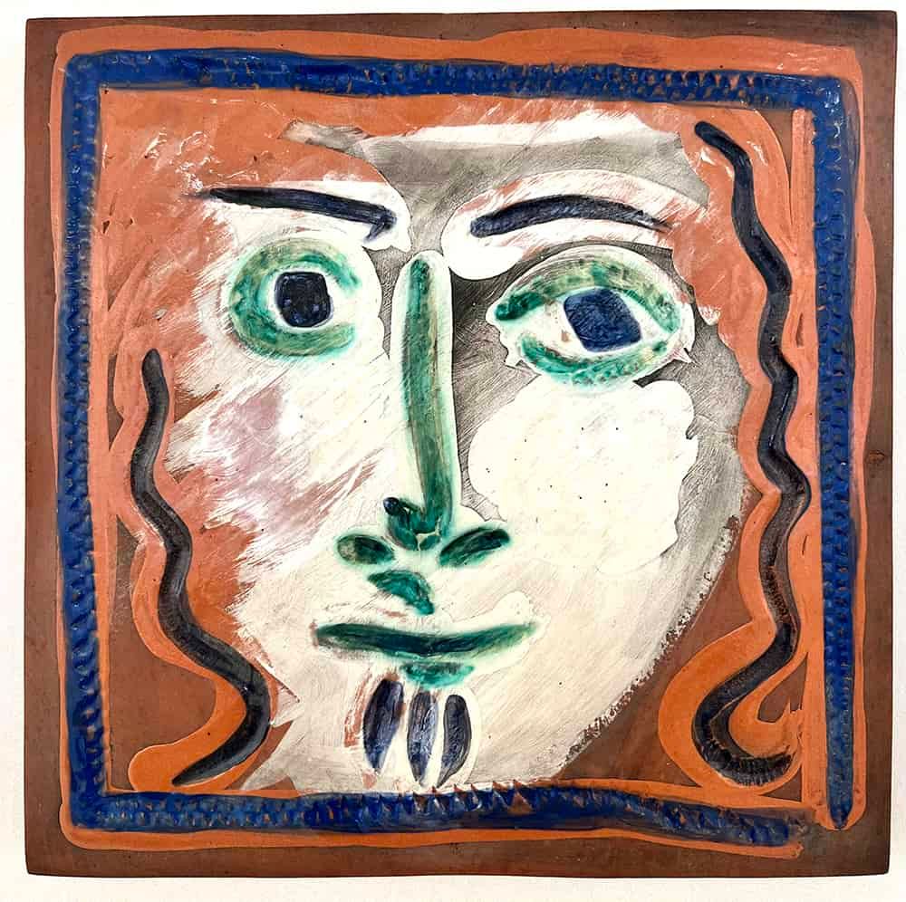 Square ceramic tile with a Picasso-style face; brown, white, orange, blue and green colors.