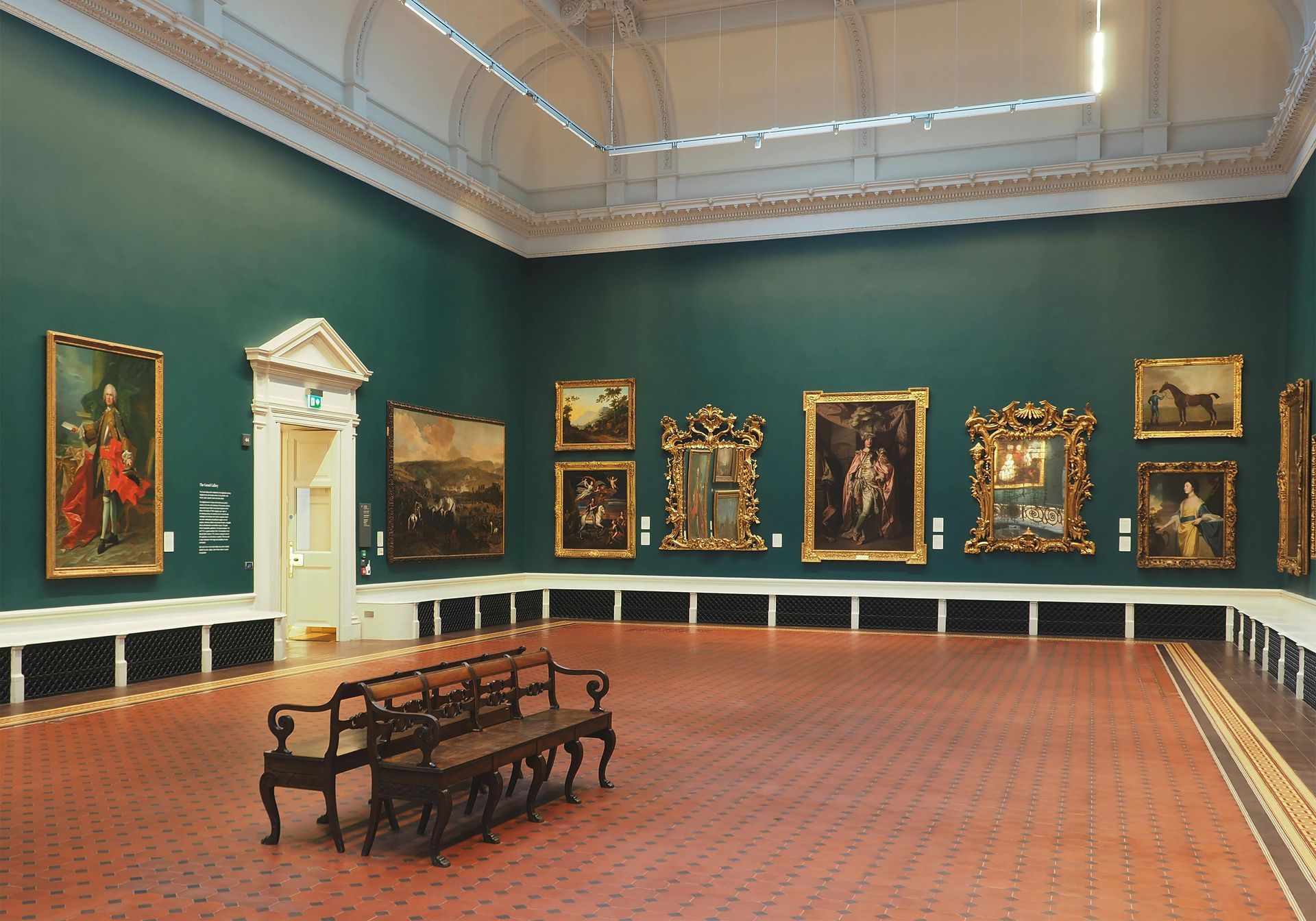 An art gallery with green walls, a tiled floor, and numerous framed paintings. A wooden bench sits in the foreground.