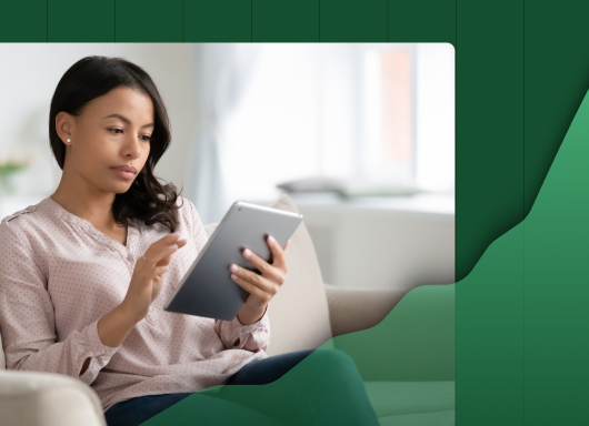 a woman is sitting on a couch using a tablet