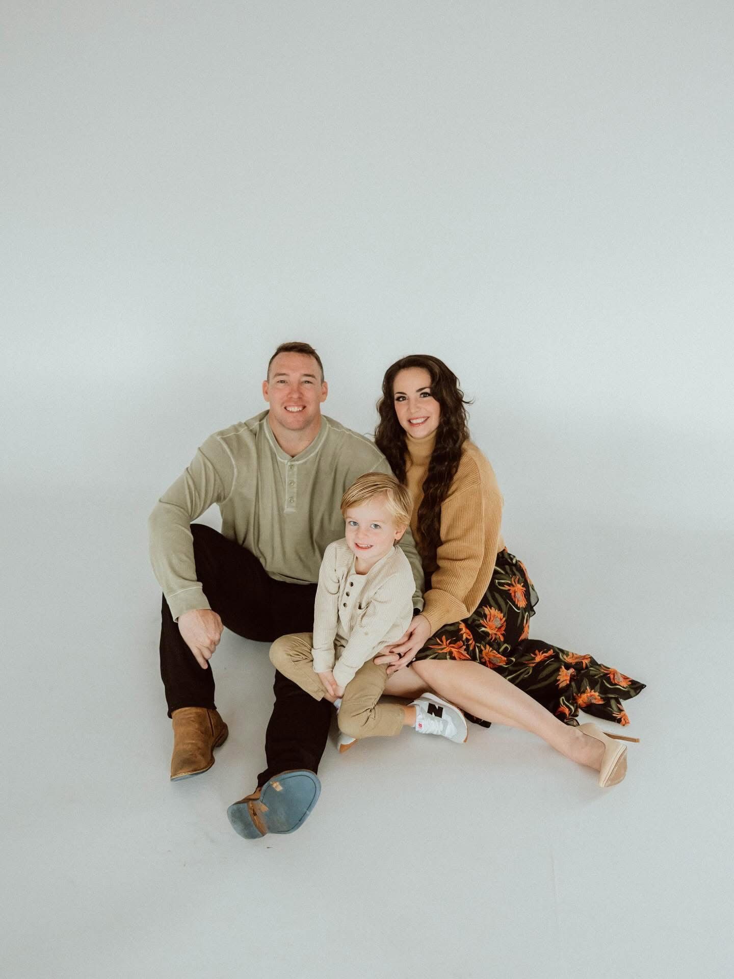 Football coach with arms crossed, standing on a football field. He wears a navy polo shirt and gray pants.