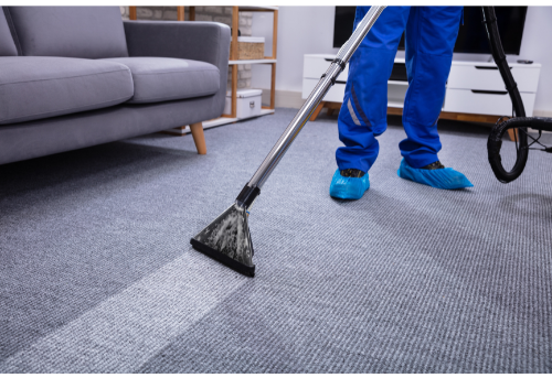 A person is cleaning a carpet with a vacuum cleaner in a living room.