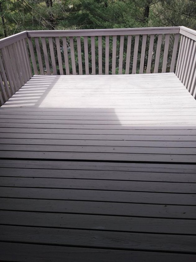 A wooden deck with a railing and trees in the background