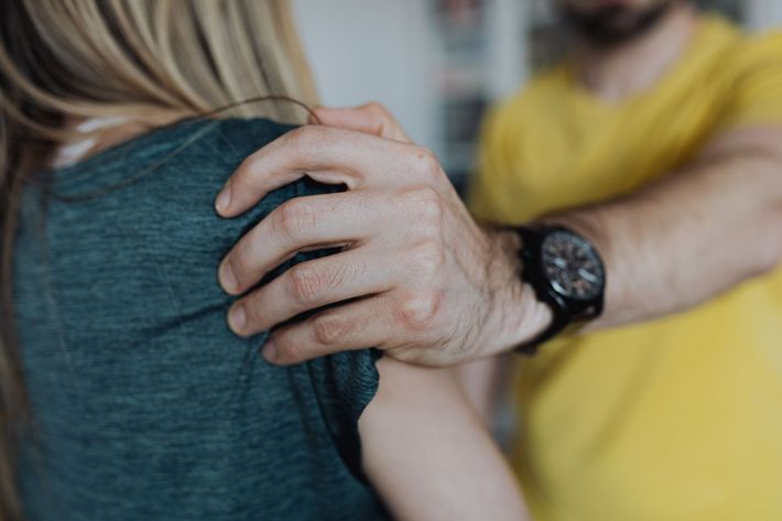 Man in yellow shirt comforting someone by the shoulder, with a black watch visible