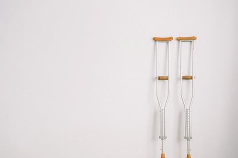 A pair of crutches hanging on a white wall.