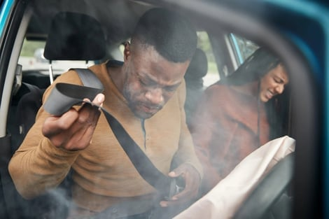 A man is sitting in a car with smoke coming out of the window.