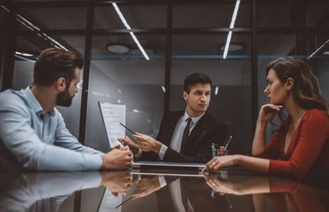 A man and a woman are sitting at a table having a meeting with a lawyer.