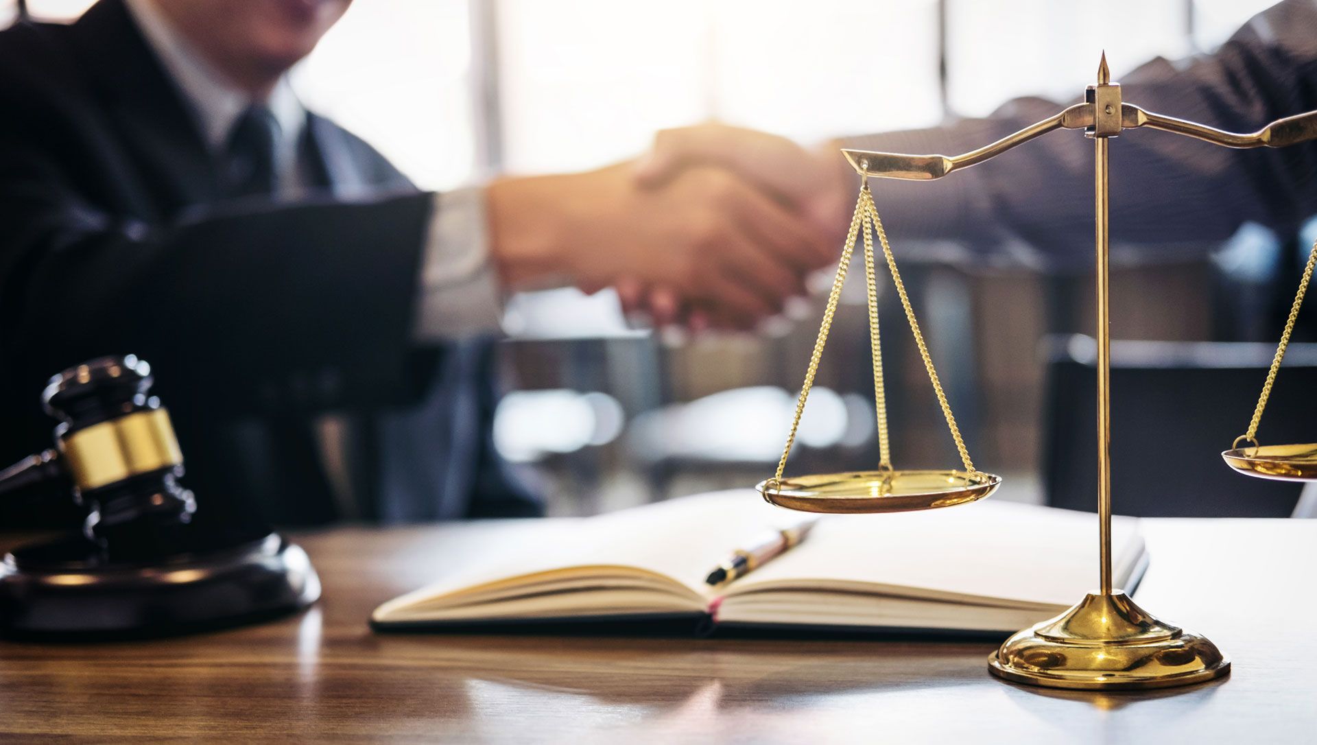 A judge is shaking hands with a client in front of a scale of justice.