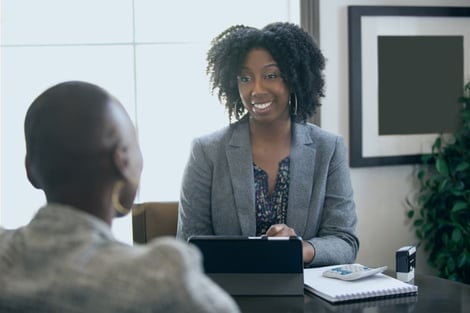 A woman is sitting at a table talking to a man.