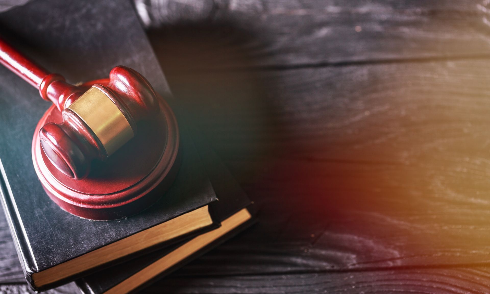 A judge 's gavel is sitting on top of a stack of books on a wooden table.