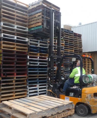 Man working with new and used pallets in Melbourne