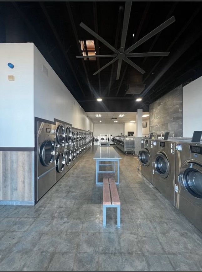a laundromat with lots of washing machines and a bench | Fresno, CA | ALCO Services
