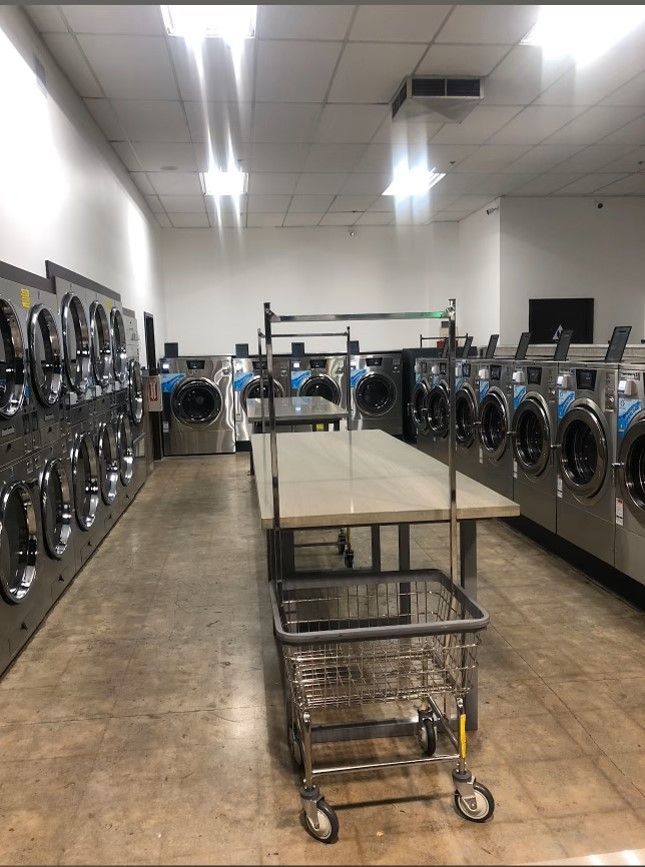 a laundromat filled with lots of washing machines and a table . | Fresno, CA | ALCO Services