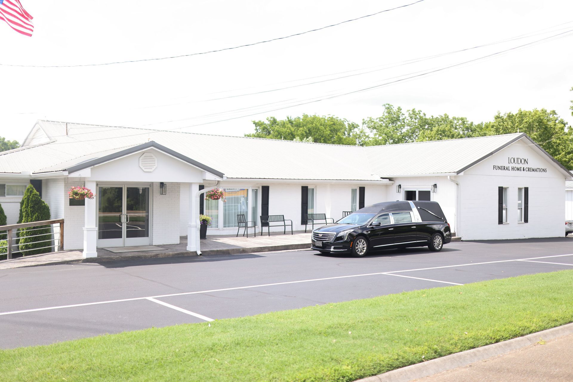 A black car is parked in front of a white building