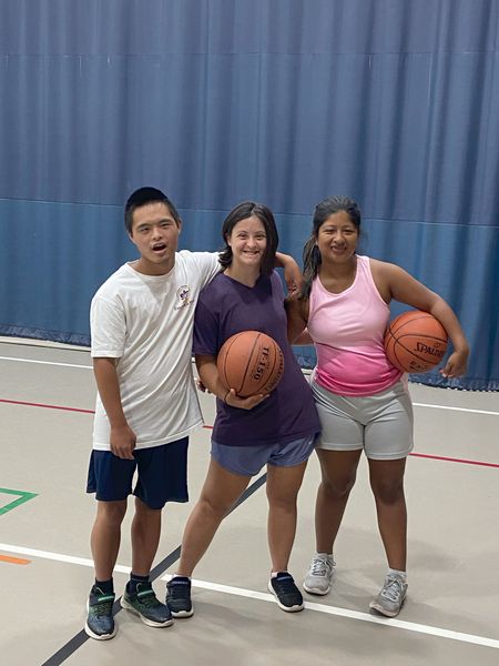 A woman is doing a pull up on gymnastic rings in a gym.