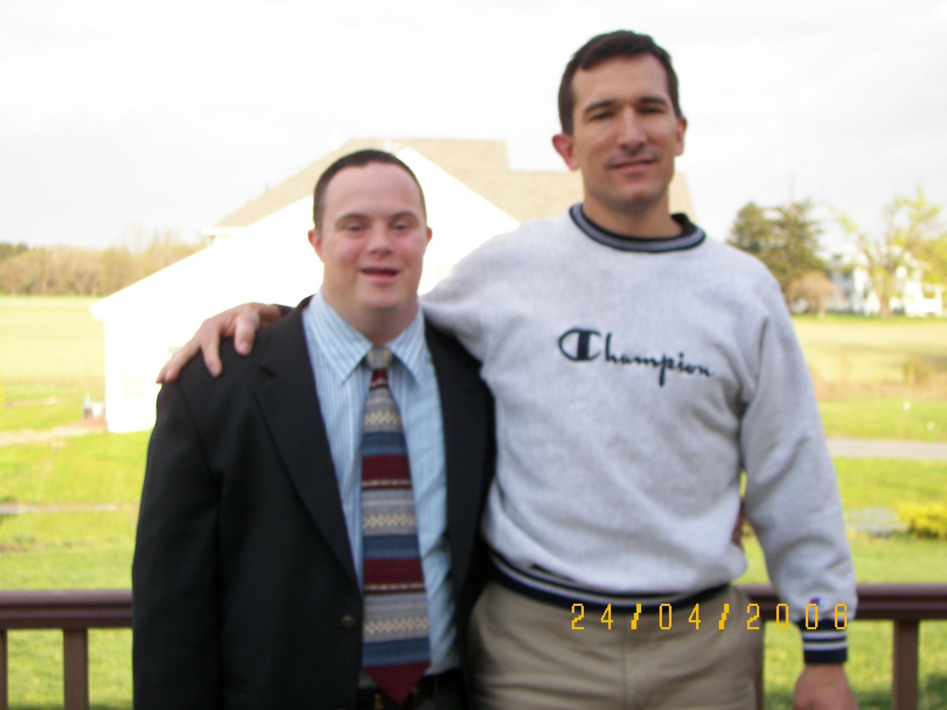 Two men posing for a picture with one wearing a champion sweater