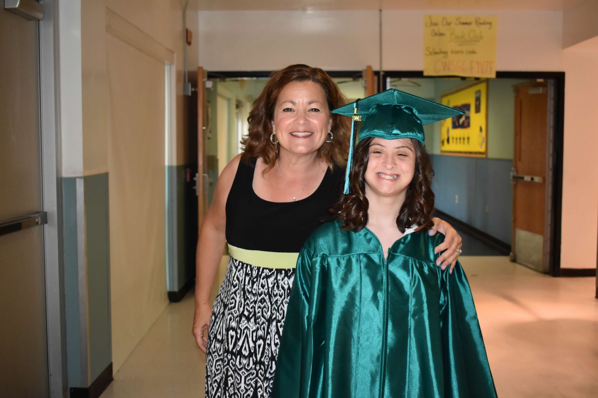 A woman and a girl are posing for a picture in a hallway.