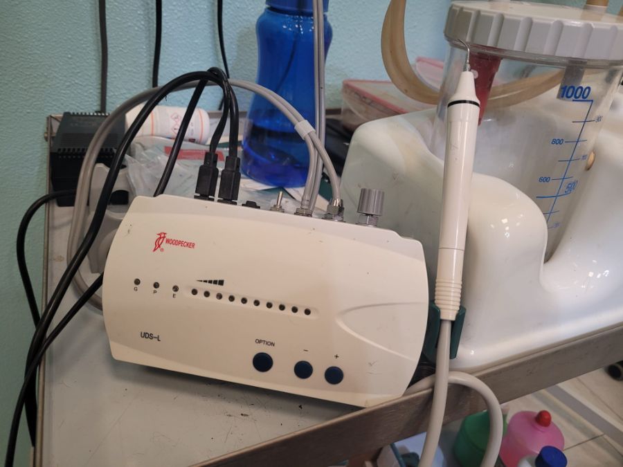 Dispositivo medico con più fili e un manipolo, accanto a un contenitore per l'acqua.