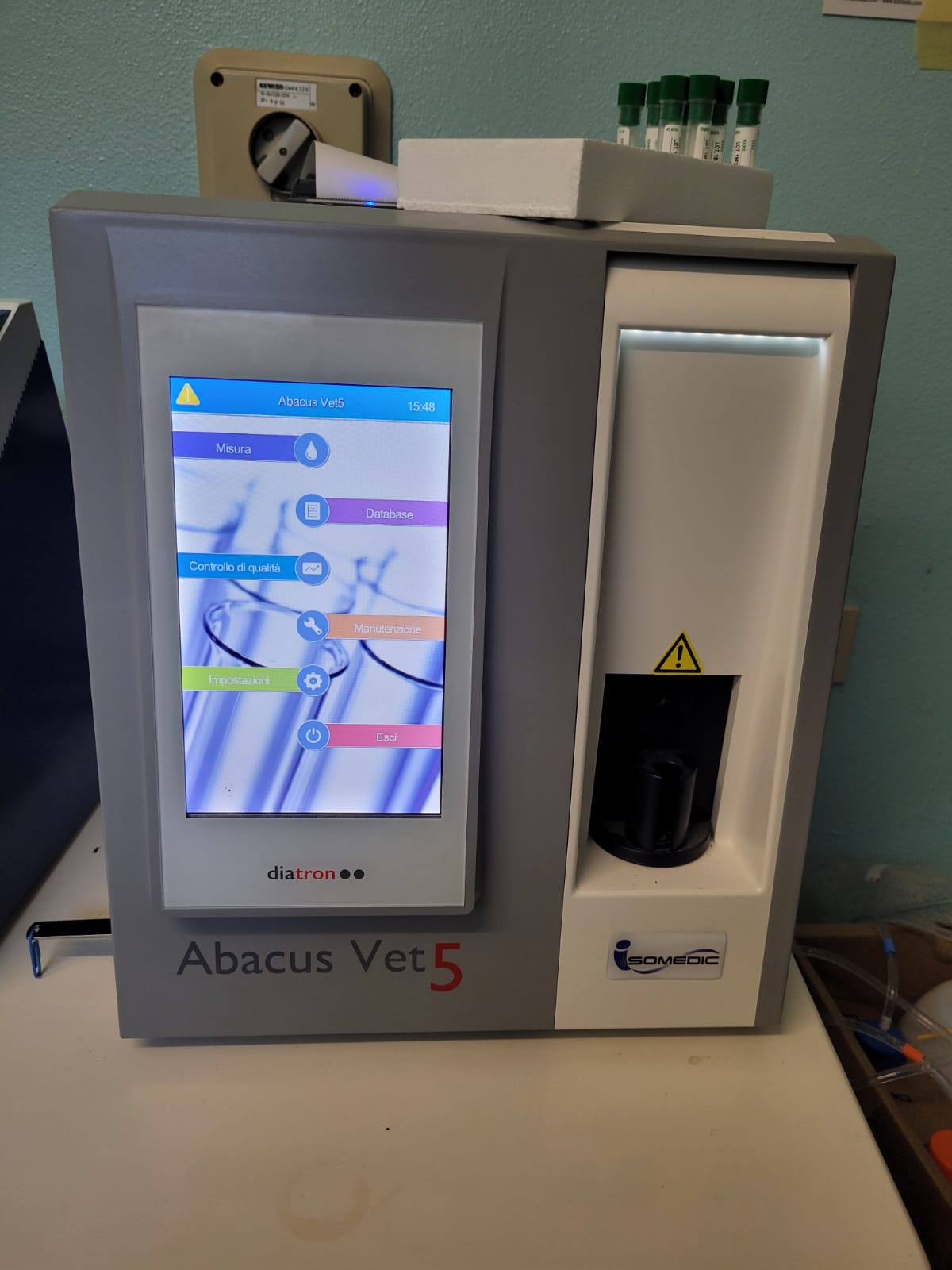 Analizzatore del sangue Abacus Vet 5 con interfaccia touchscreen a colori, provette e apertura scura.