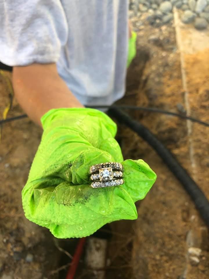 A person is holding a pair of wedding rings on a green cloth.