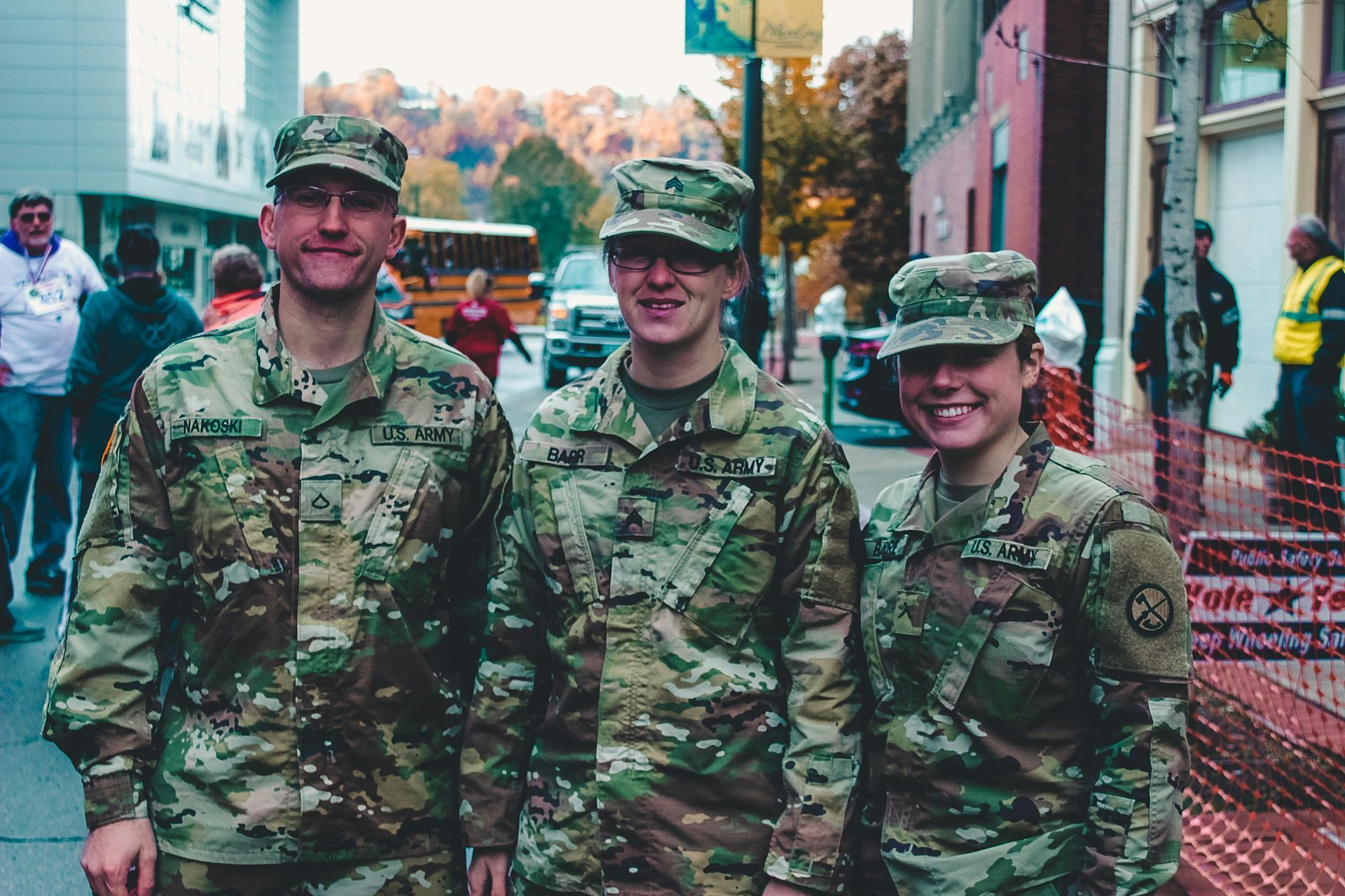 Three soldiers are posing for a picture on a city street.