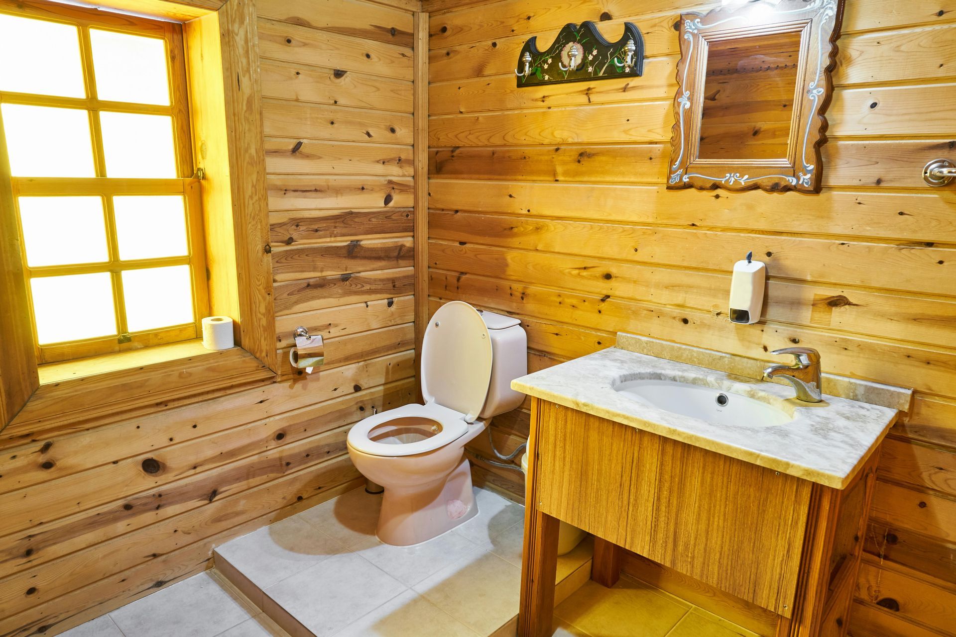 A wooden bathroom with a toilet , sink and mirror
