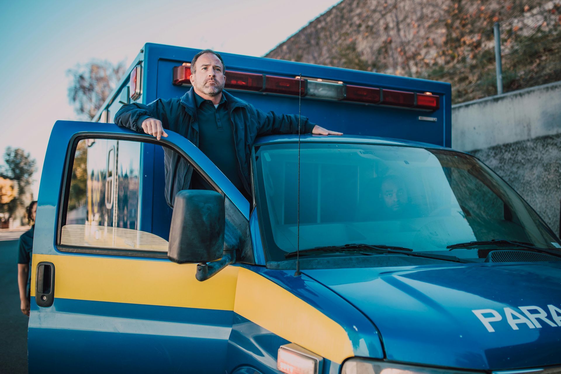 A man is standing next to an ambulance on the side of the road.