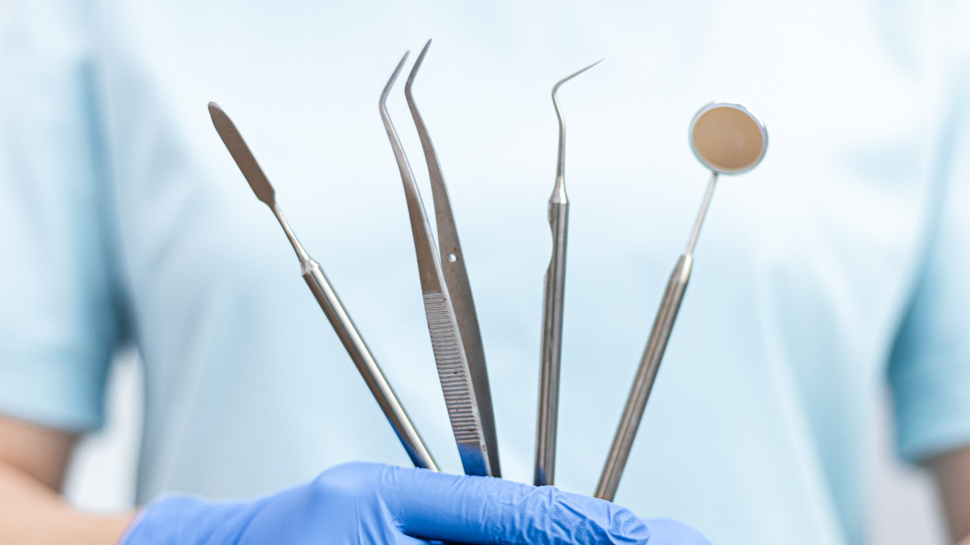 A young boy is sitting in a dental chair giving a thumbs up.