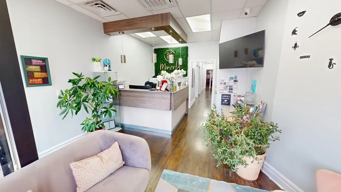 A living room with a couch , table and plants in a dental office.