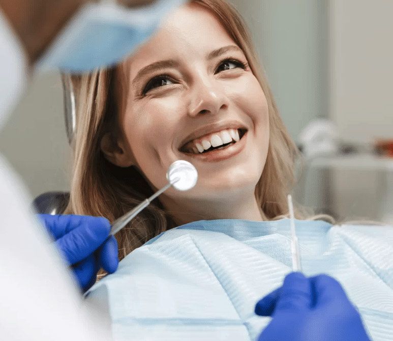 A woman is smiling while having her teeth examined by a dentist. - Mercury-Free Dentist