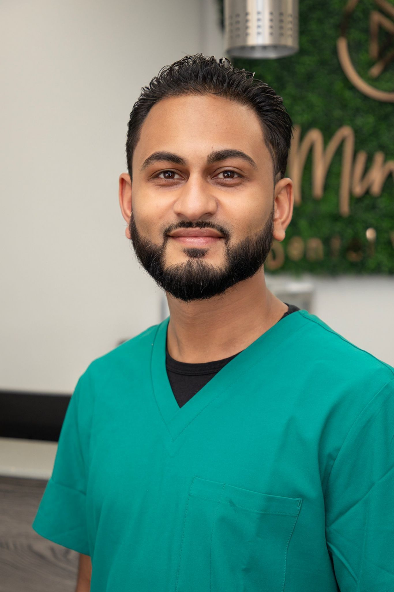 A man with a beard is wearing a green scrub top.