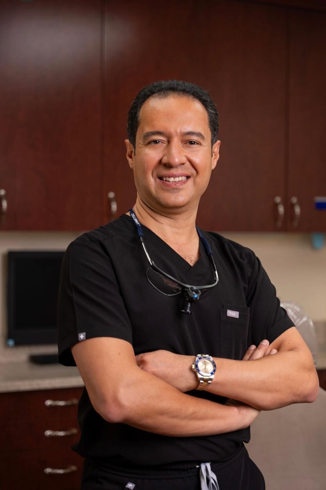 A man in a white coat and tie is smiling for the camera.