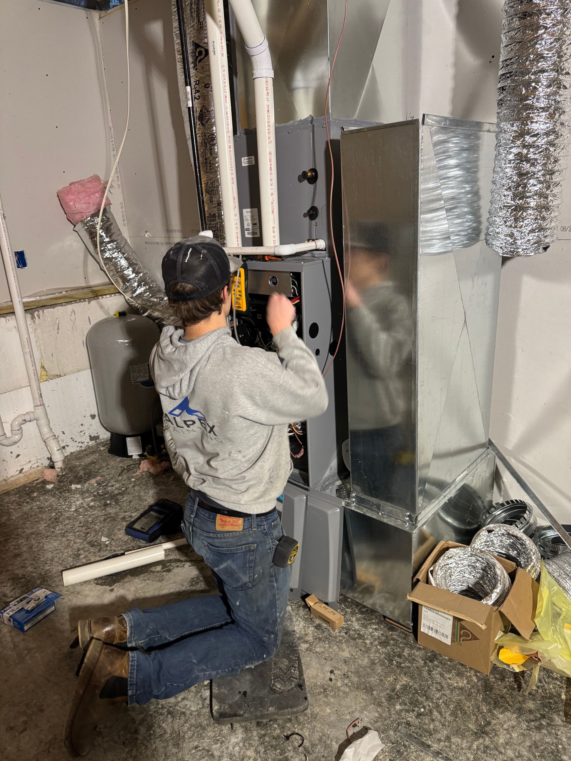 A man wearing a mask is working on an air conditioner on a roof.