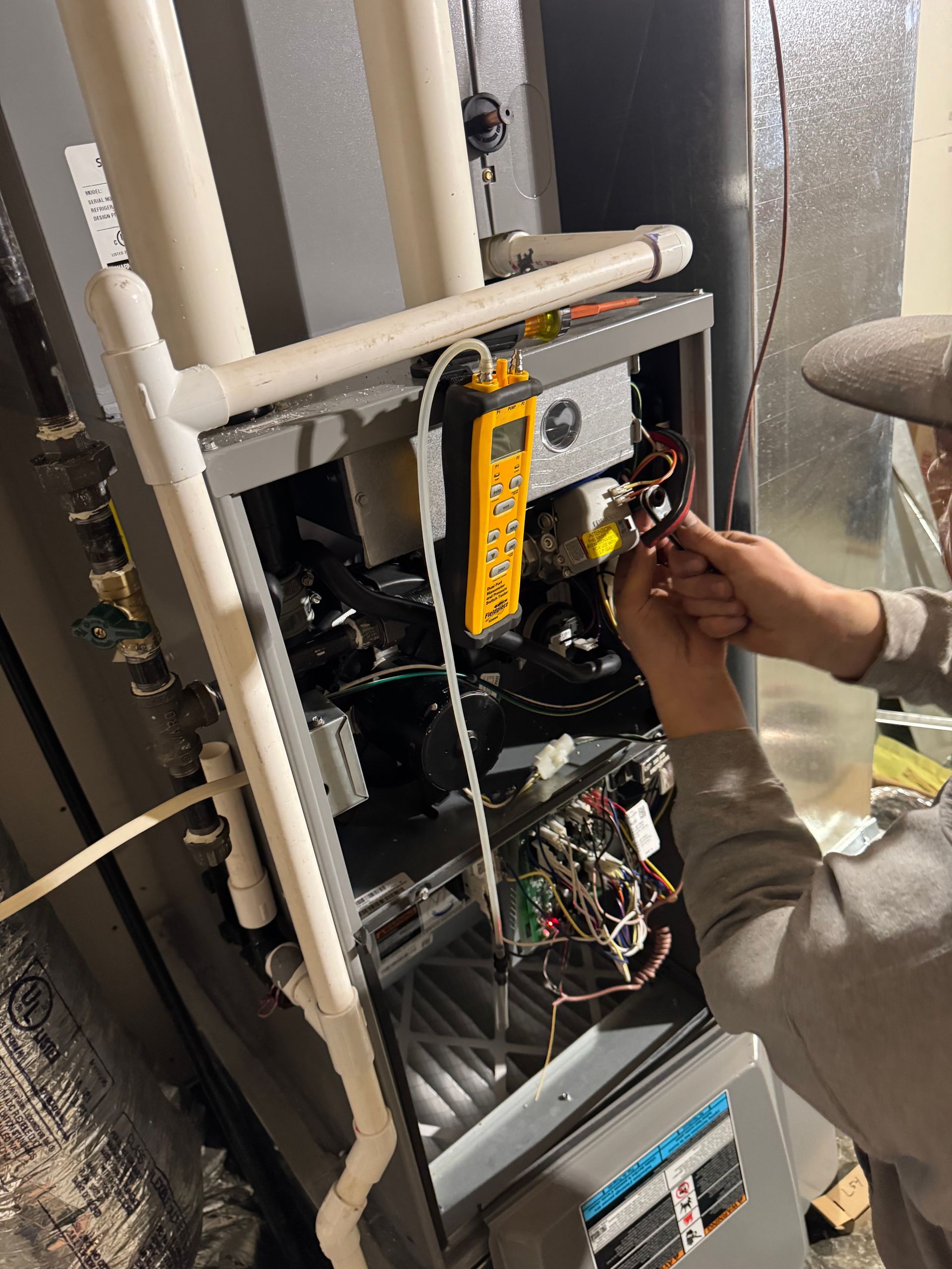 A man wearing a mask is working on an air conditioner.