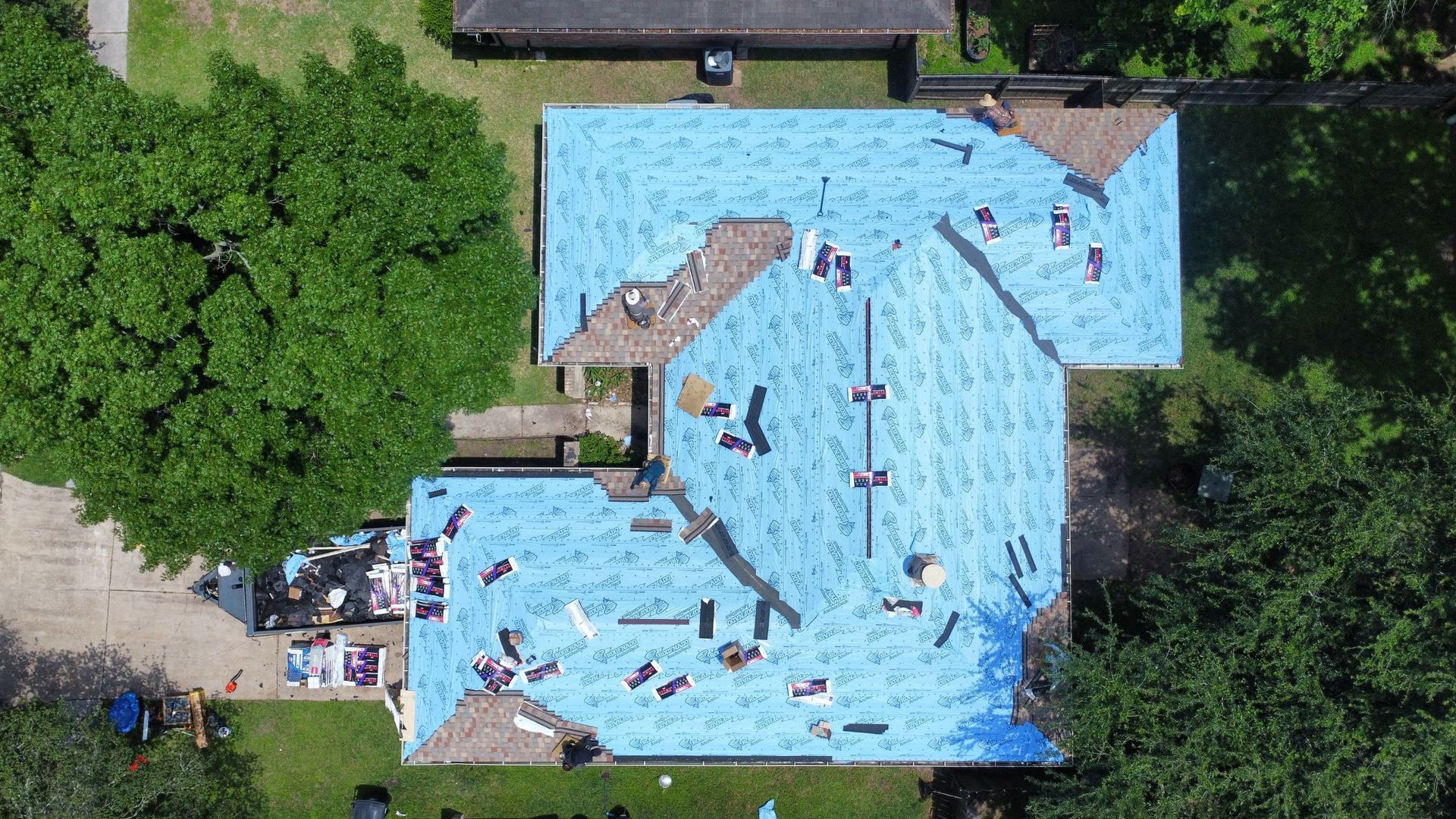 Aerial view of a crowded outdoor swimming pool with people floating and swimming in bright blue water.