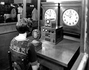 A black and white photo of a woman sitting in front of a clock.