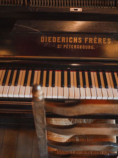 Diederichs Frères upright piano with visible keys and worn wooden bench in warm indoor light