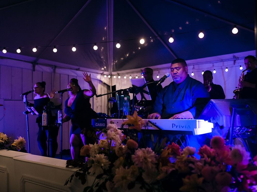 Live band performing on stage at night, under string lights. 