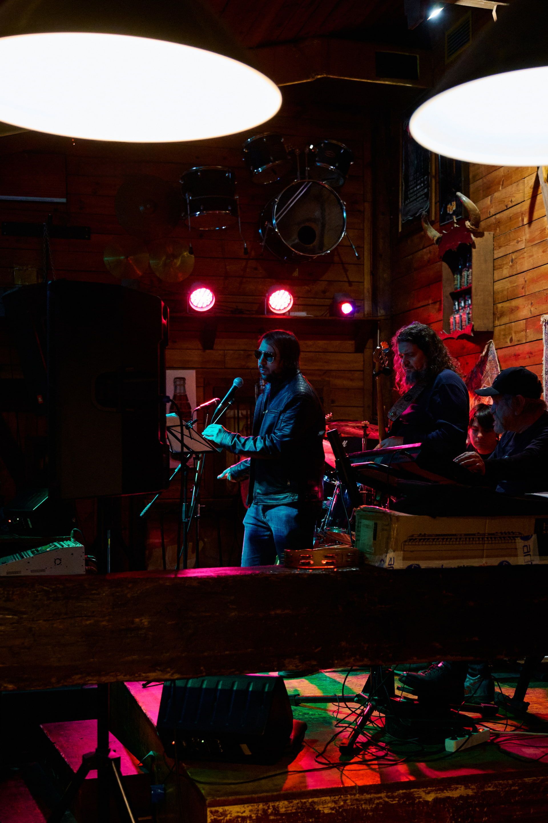 Band performing on a stage with a microphone and keyboard in a dimly lit bar.