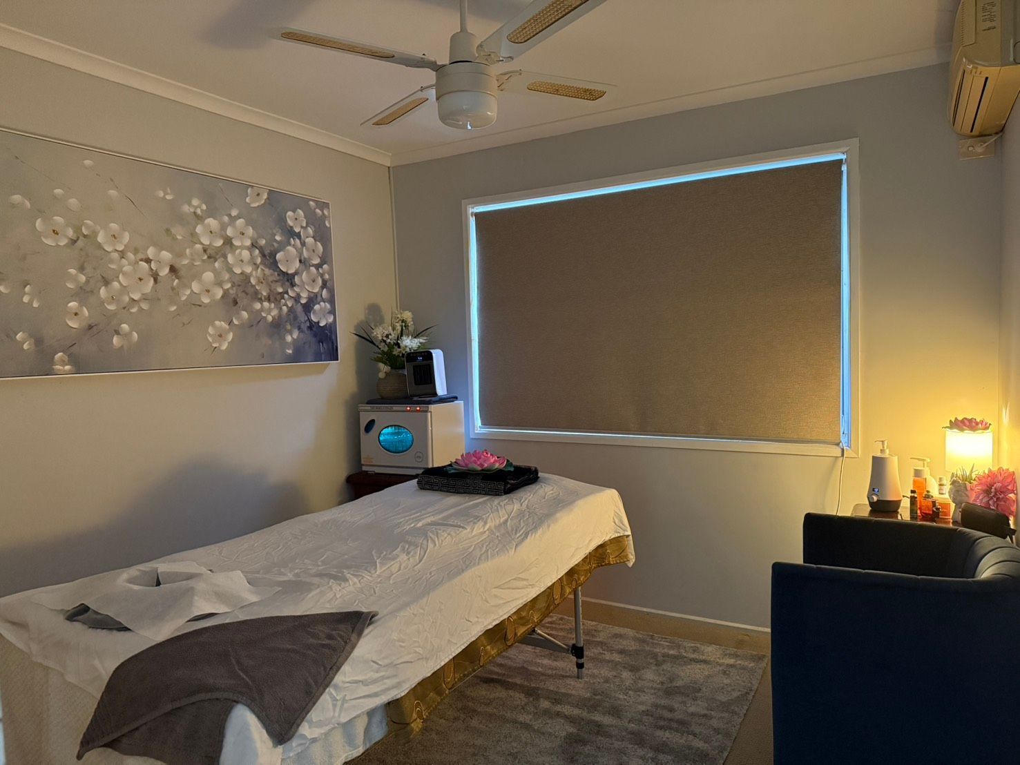 A room with a massage table and a ceiling fan at Sarah's Thai Massage Paradise Point.