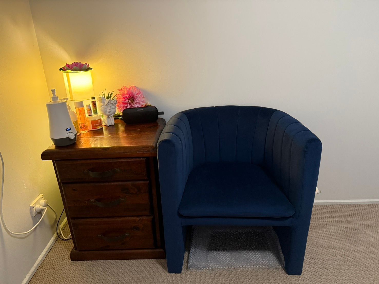 A blue chair is sitting next to a nightstand in a room Sarah's Thai Massage Paradise Point.