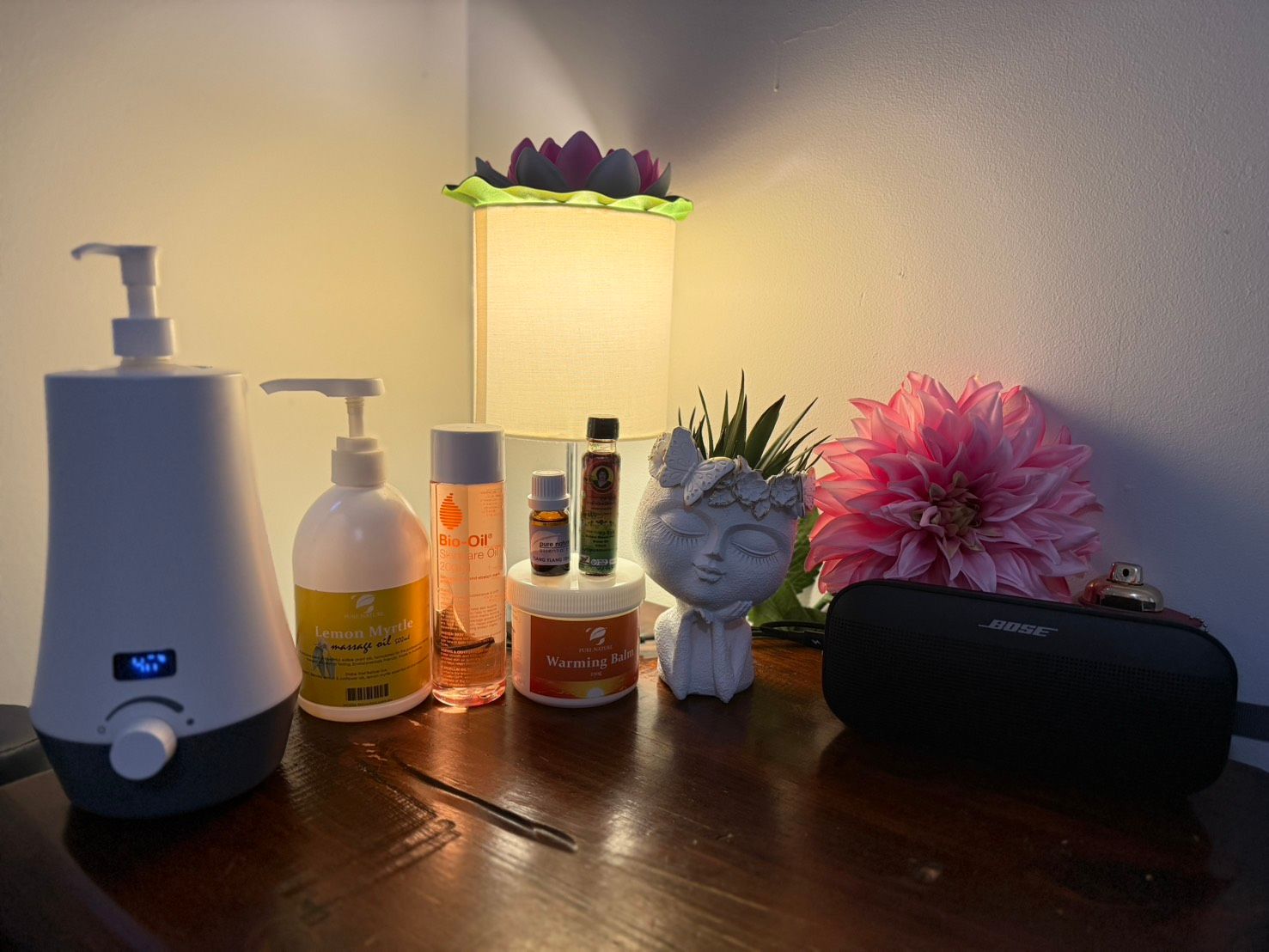 A table with a humidifier , bottles of essential oils , a lamp and a speaker at Sarah's Thai Massage Paradise Point.