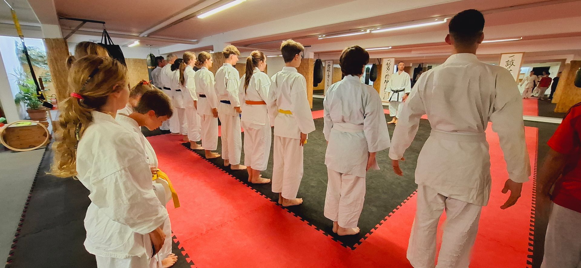 Karateka in weißen Karategis stehen in Reihe zur Begrüßung im Kampfsport-Training der Karateschule Thun und Spiez.